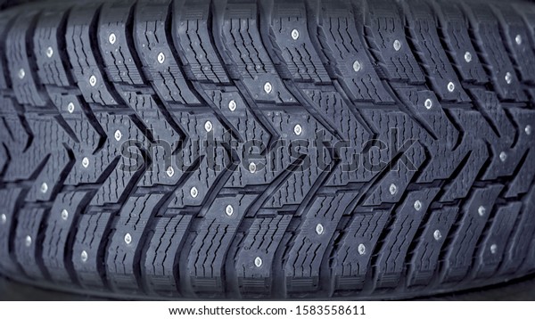 Winter tires for car.\
Radial tread, thin lamellas and metal spikes. New, not worn out car\
tires. Safe driving on a snowy and winter road. Part of the image\
is blurred.