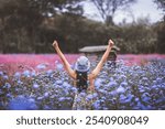 Winter travel relax vacation concept, Young happy traveler asian woman with dress sightseeing and open arm on blue flower field in garden at Khao Yai, Thailand