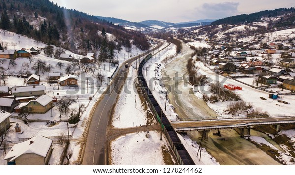 Winter travel. Train\
and bus moving in winter valley. Aerial view of river Dniester in\
Carpathian mountains.