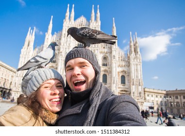 Winter travel and vacations concept - Happy tourists taking a self portrait with funny pigeons in front of Duomo cathedral in Milan