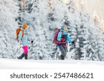 winter trekking. two girls with backpacks and snowshoes. walking in the snow among the trees. winter hike in the mountains. adventure in the mountains.