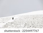 Winter trekking uphill in winter mountains, through snow and heading to mountaintop. Concept of mountaineering, alpinism and alpine climbing