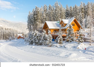 Winter Vacation Holiday Wooden House In The Mountains Covered With Snow And Blue Sky.