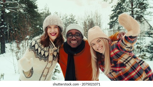 Winter Vacation Together. Three Multiethnic Happy Friends Wave, Smile At Camera At Beautiful Snowy Forest Slow Motion.