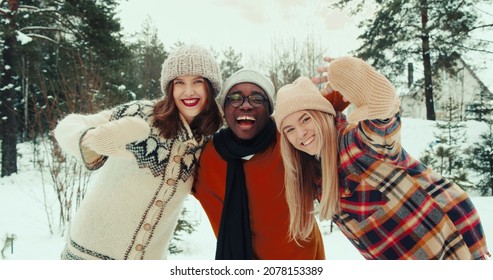 Winter Vacation Together. Three Multiethnic Happy Friends Wave, Smile At Camera At Beautiful Snowy Forest Slow Motion.