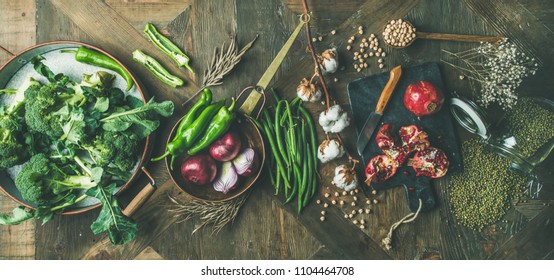 Winter vegetarian, vegan food cooking ingredients. Flat-lay of seasonal vegetables, fruit, beans, cereals, kitchen utencils, dried flowers, olive oil over wooden background, top view, wide composition - Shutterstock ID 1104464708