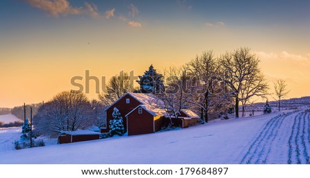 Winter view of a barn on a snow covered farm field at sunset, in rural York County, Pennsylvania.