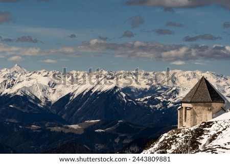 Winter view from Mount Dobratsch with the Windish Chapel in the foreground, and the snow-covered Alps including Mount Grossglockner in the background.