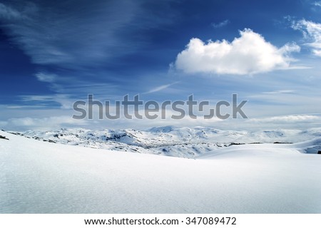 Winter view on mountain range. Pure white snow field. Blue sky, white cloud. Norway.