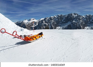 Winter. View of the sleigh for transporting victims on the ski slope against the backdrop of the bare snow-covered cliffs of the Dolomites in the ski resort. 
