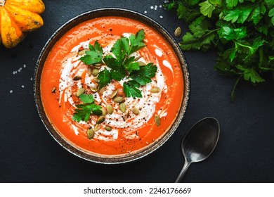Winter warming spicy pumpkin soup with seeds, cream, pepper and parsley. Healthy comfort slow food. Soup bowl on black table background. Top view - Shutterstock ID 2246176669