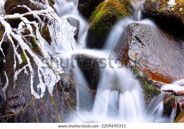 Winter water cascade long exposure . Flowing\
water over stones in\
wintertime