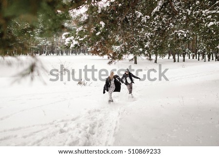 Winter weekend. Happy couple running in the winter forest