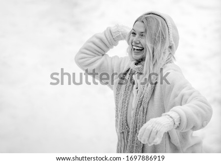 Winter woman. Cute playful young woman outdoor enjoying first snow. Happy young girl playing snowball fight. Girl in mittens hold snowball