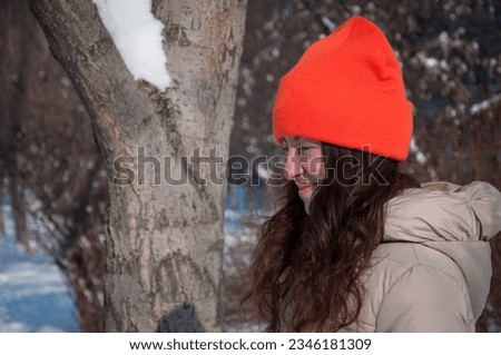 winter woman in orange warm hat in snow wintertime, copy space. winter fashion of woman in warm hat with wintertime snow.