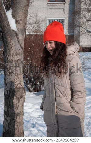 winter woman standing in orange warm hat in snow wintertime. winter fashion of woman in warm hat with wintertime snow.