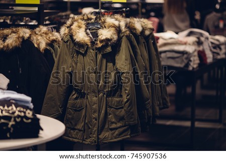 Winter women clothes in clothing store. Women's winter parka with a fur hood in the women's clothing store ready for sale