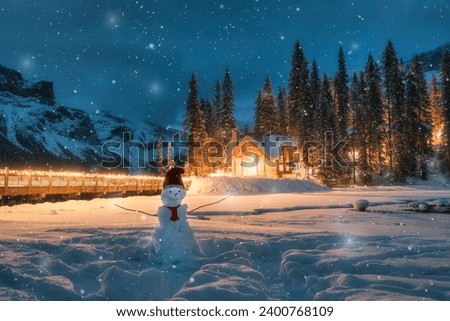 Winter wonderland of Emerald Lake with wooden cottage and snowman with santa hat in falling snow at Yoho national park, British Columbia, Canada