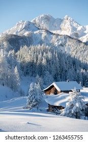 Winter Wonderland In Mountains. Winter Vacation Holiday Wooden House In The Mountains Covered With Snow. Pine Trees Forest And Blue Sky In The Background. Vertical Shot