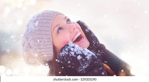 Winter Young Woman Portrait. Beauty Joyful Model Girl Touching Her Face Skin And Laughing, Having Fun In Winter Park. Beautiful Young Woman Laughing Outdoors. Enjoying Nature, Wintertime