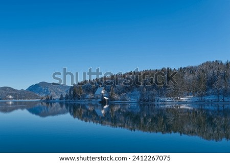 Winterlandscape at a lake with mirroring, reflections and blue sky in Bavaria, central Europe