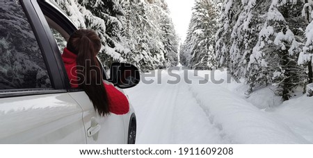 Wintertime,  enjoying, relaxing, tourism, travel, leisure time, adventure, vacation mode concept. Young woman with red sweater  enjoying a road trip in the white car on a forest road.  