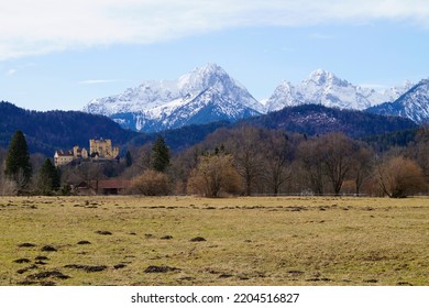 wintery Bavarian alpine village Schwangau with the snowy Alps and Hohenschwangau Castle (Schloss Hohenschwangau) in the background (Bavaria, Allgaeu, Germany)                               