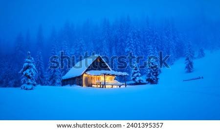 A wintery scene in the heart of the woods with a solitary wooden cottage and snow-draped pine trees on a mountain glade. Christmas postcard. Snowy mountains forest