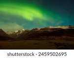 Wintry landscape with aurora borealis above snow covered mountain peaks. Icelandic northern lights magnificent natural phenomenon that brighten up sky, arctic region with magic reflections.