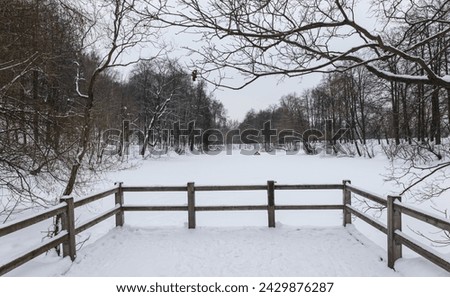 A wintry landscape filled with snow-covered trees and a splitrail fence, as a building stands tall against the freezing sky during a fierce blizzard