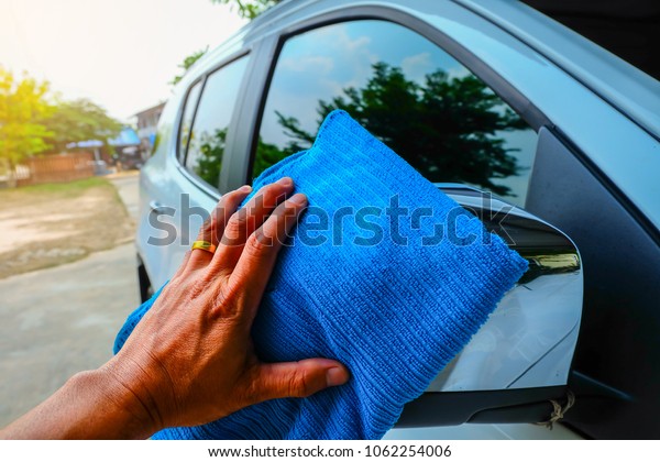 Wipe the car. A man cleaning\
car with microfiber cloth, car detailing concept. Selective\
focus.