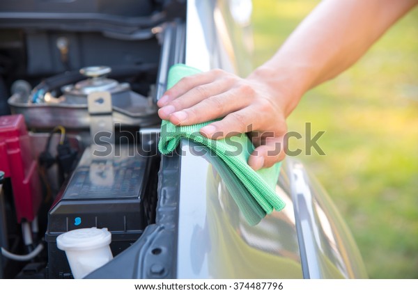 Wipe cleaning the car engine with green\
microfiber cloth\
