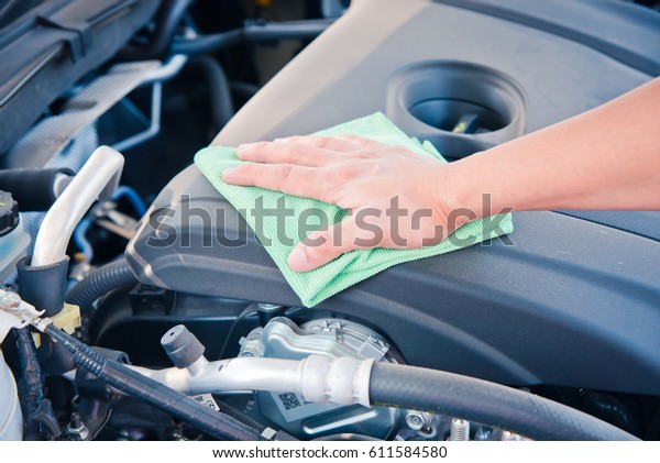 Wipe\
cleaning the car engine with green microfiber cloth\
