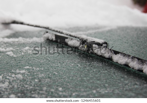 Wiper blade clean the\
icy windshield of the car from snow, top view close up - winter,\
snowstorm, icing vehicle after snowfall, safety winter driving,\
preparation for the trip