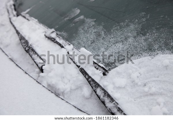 Wiper blades clean the car\'s\
windshield from snow - winter, snowstorm icing vehicle after\
snowfall, safe winter driving traffic, preparing for the\
trip