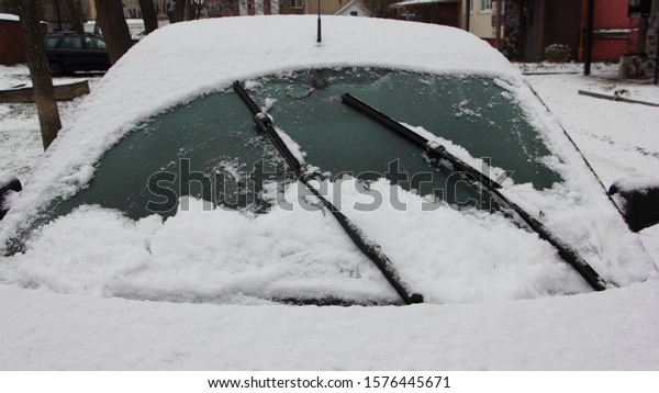 Wiper blades\
clean the snowy car windshield from snow, outdoor close up front\
view - winter, snowstorm,\
snowfall