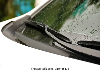 Wipers on windshield of car close up on rainy day. Shallow depth of field, focus on wiper