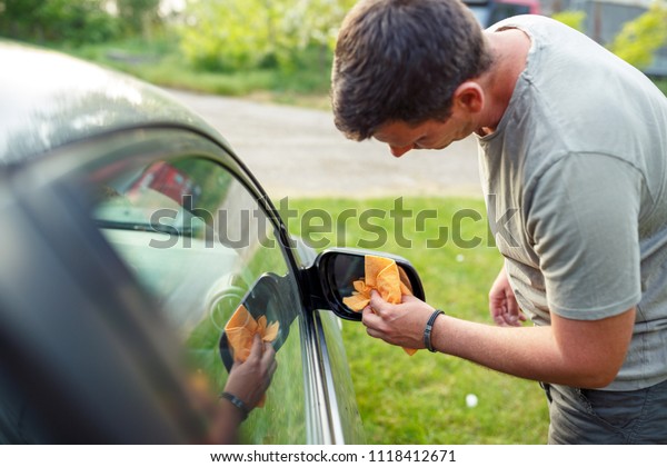 Wiping car- Young man cleaning car with\
microfiber cloth, car\
detailing\
