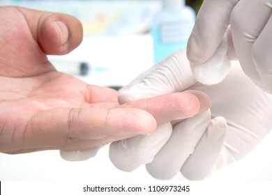 Wiping finger with medical alcohol, taking a blood sample from a man.