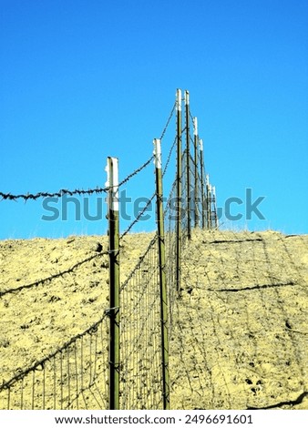 A wire fence in California along a north-south intertate.