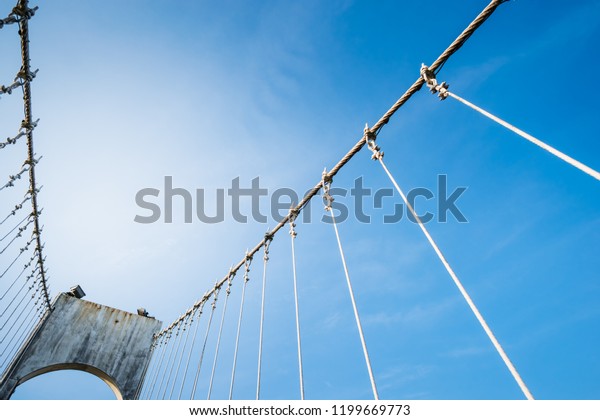 The wire\
metal rope bridge on blue sky\
background