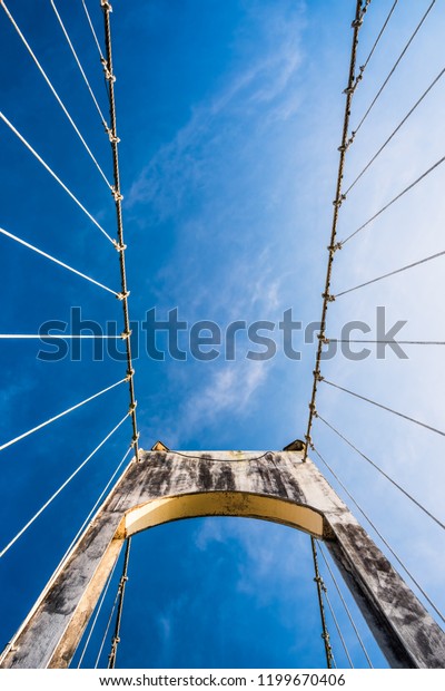 The wire\
metal rope bridge on blue sky\
background