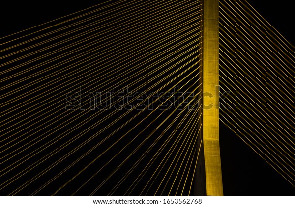 Wire Rope Sling of Suspension\
bridge with golden light in the night time, selective\
focus