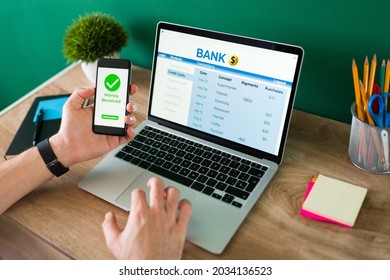 Wire Transfer. Young Man Using His Smartphone And Laptop To Do A Banking Transaction And Some Payments 