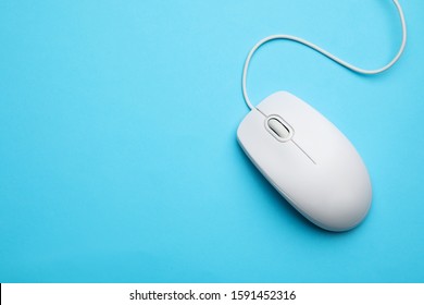 Wired computer mouse on light blue background, top view. Space for text
