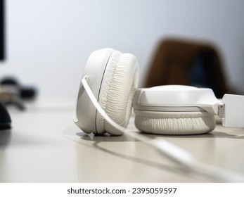 wired headphones close up on a desk with monitors on background.  - Shutterstock ID 2395059597