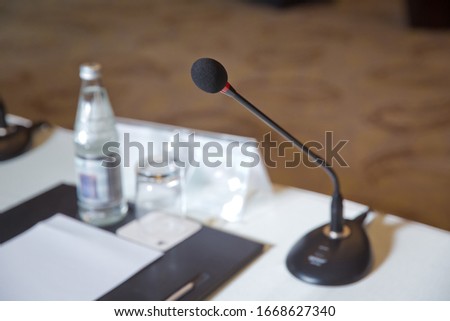 Wired microphone set up on the front of conference room close up with blurred background. Wired microphone close up with copy space . Close up of microphone in concert hall or conference room .
