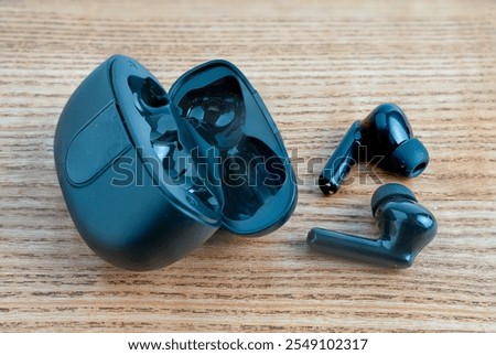 wireless bluetooth audio ear buds for music and television internet on a wooden background