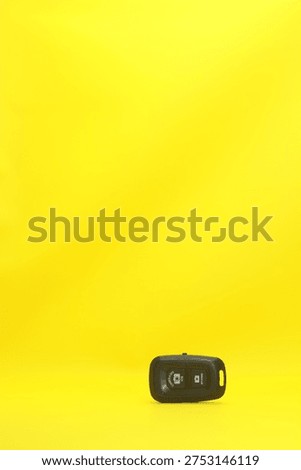 Wireless Bluetooth Camera Shutter Remote Control for iOS and Android on Minimalist Bright Yellow Background with Large Copy Space