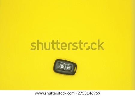 Wireless Bluetooth Camera Shutter Remote Control for Smartphones on Minimalist Bright Yellow Background
